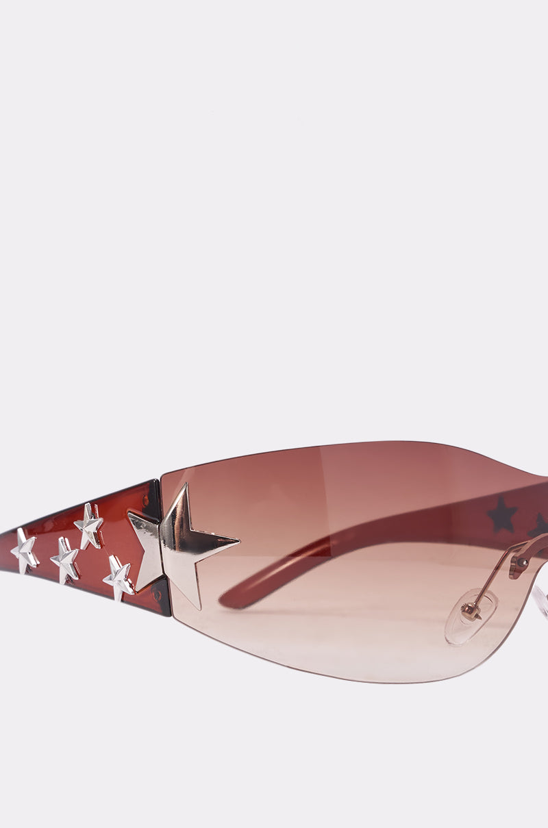 Close-up of HOTTIE ALERT SUNGLASSES with brown-tinted lenses and red arms decorated with silver star-shaped studs—perfect for standing out at any festival. 4