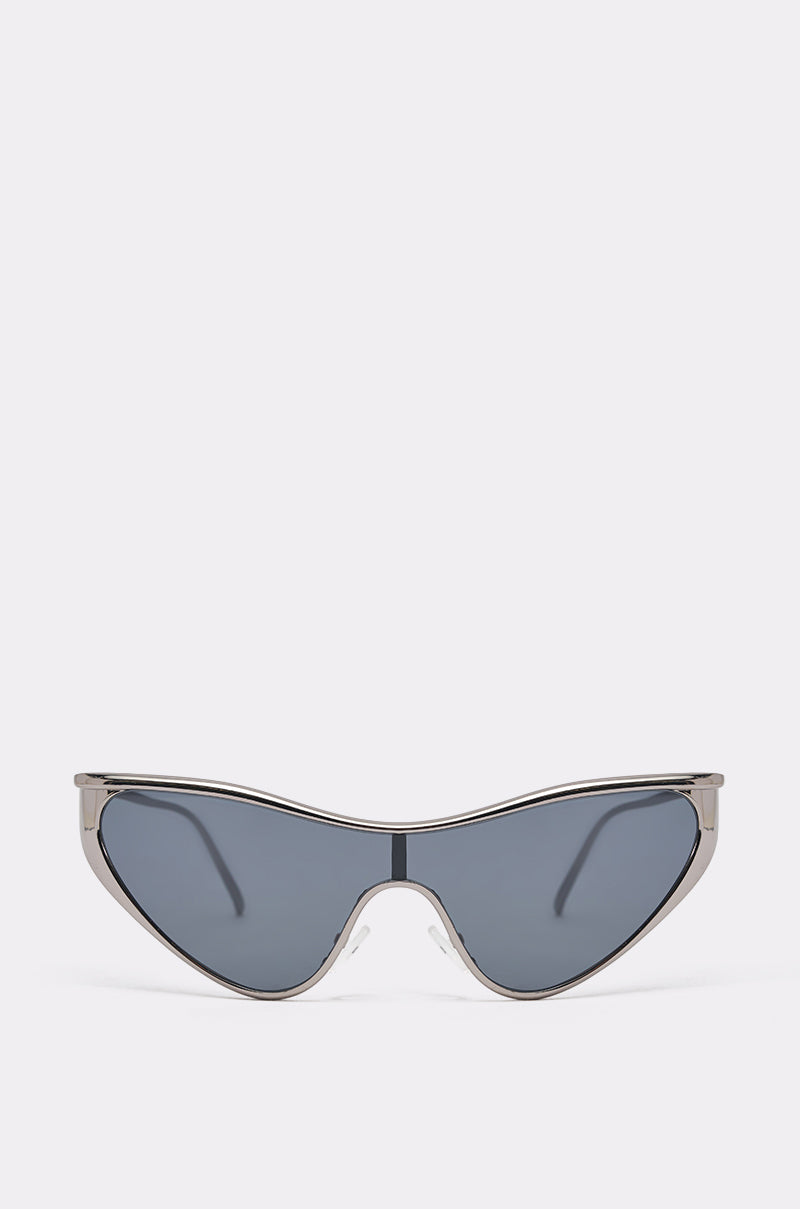 The TO THE FUTURE SUNGLASSES feature a silver-tone metal frame and large, dark-tinted angular wrap lenses, showcased against a plain light gray background for a bold, modern look. 0