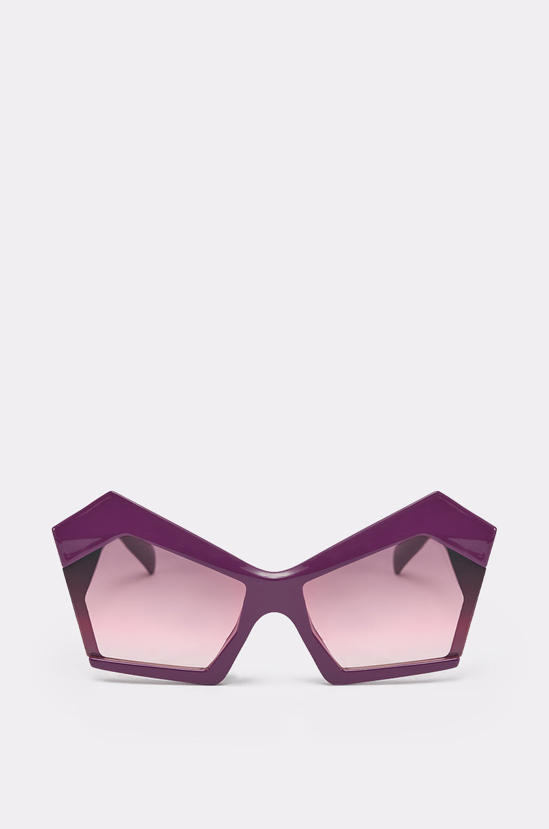 Make a statement with the ON TREND SUNGLASSES—bold, oversized geometric frames in striking purple with pink-tinted lenses and angular, pointed edges, shown against a plain white background. 0