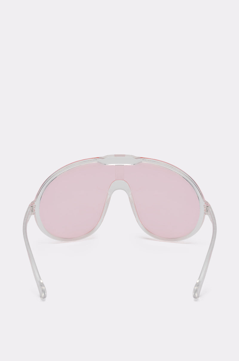 PINK VISION SUNGLASSES are displayed from the front, featuring large curved pink shield lenses and slightly outward-curved arms, set against a plain light background. 5
