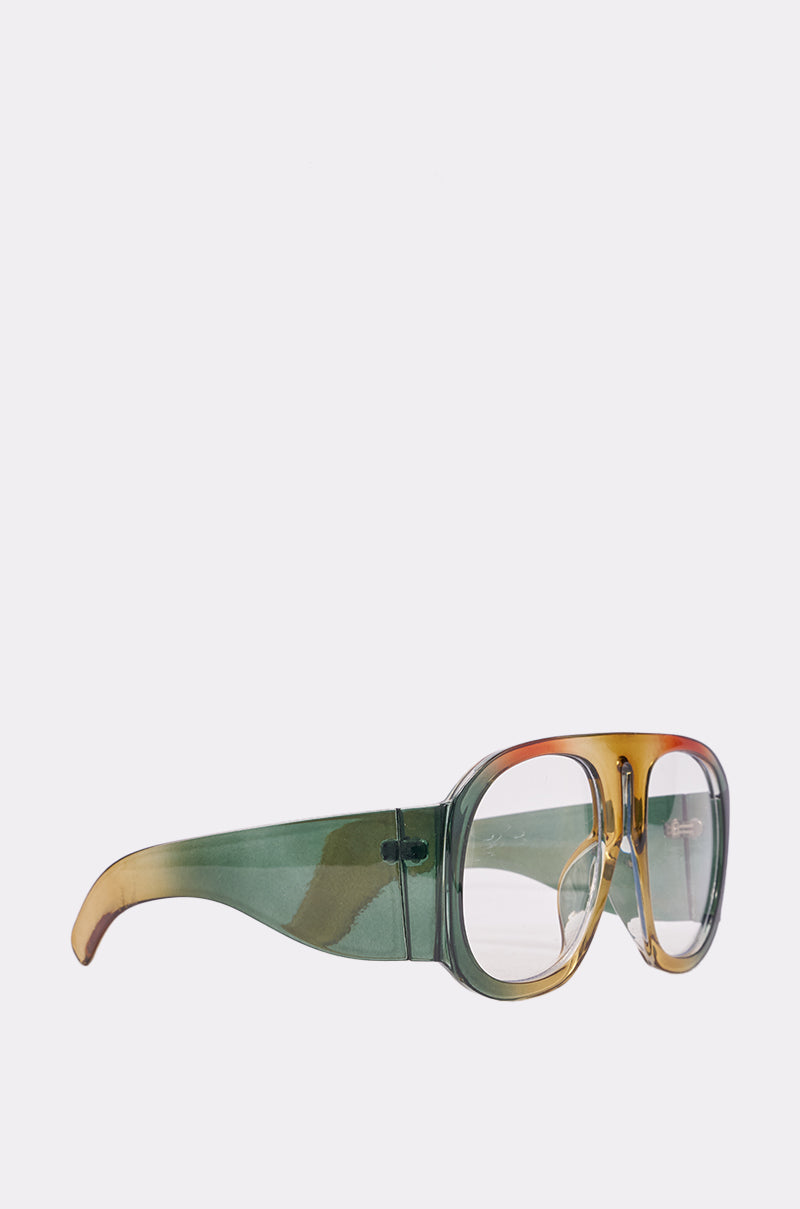 IT GIRL GLASSES are oversized brunch sunglasses with thick, transparent green and yellow gradient marbled frames and large rectangular lenses—bold statement goggles displayed on a white background. 3