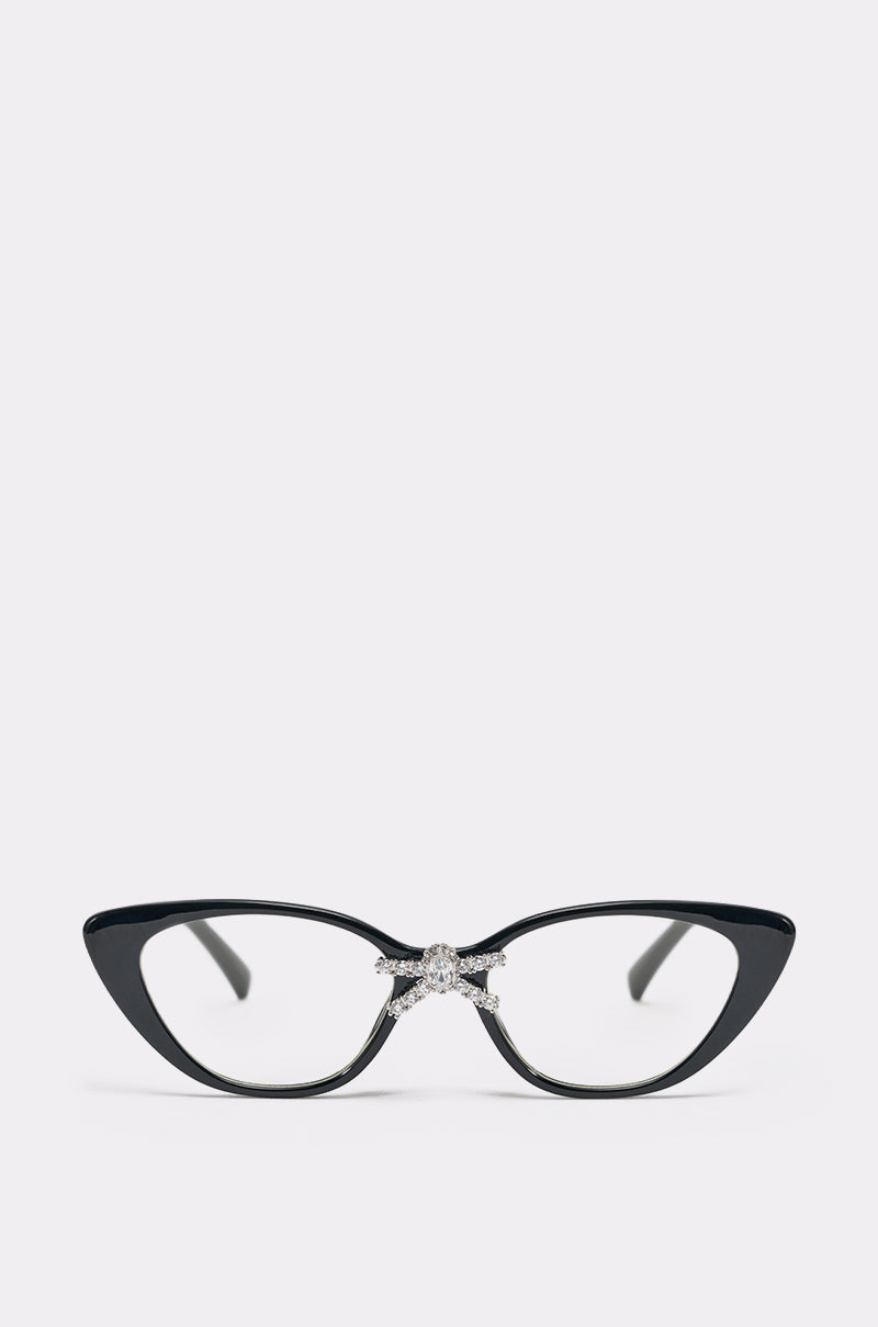 FEMME GLASSES: Black cat-eye frames featuring a sparkly, rhinestone-encrusted bow at the bridge, shown against a plain light background. 0