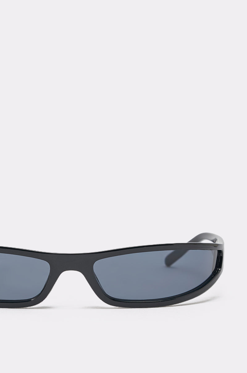 Close-up of IN THE FUTURE SUNGLASSES showcasing the top half of the black sculpted frame and dark lenses against a plain light gray background, with only the upper part of the frames and one arm in view. 4