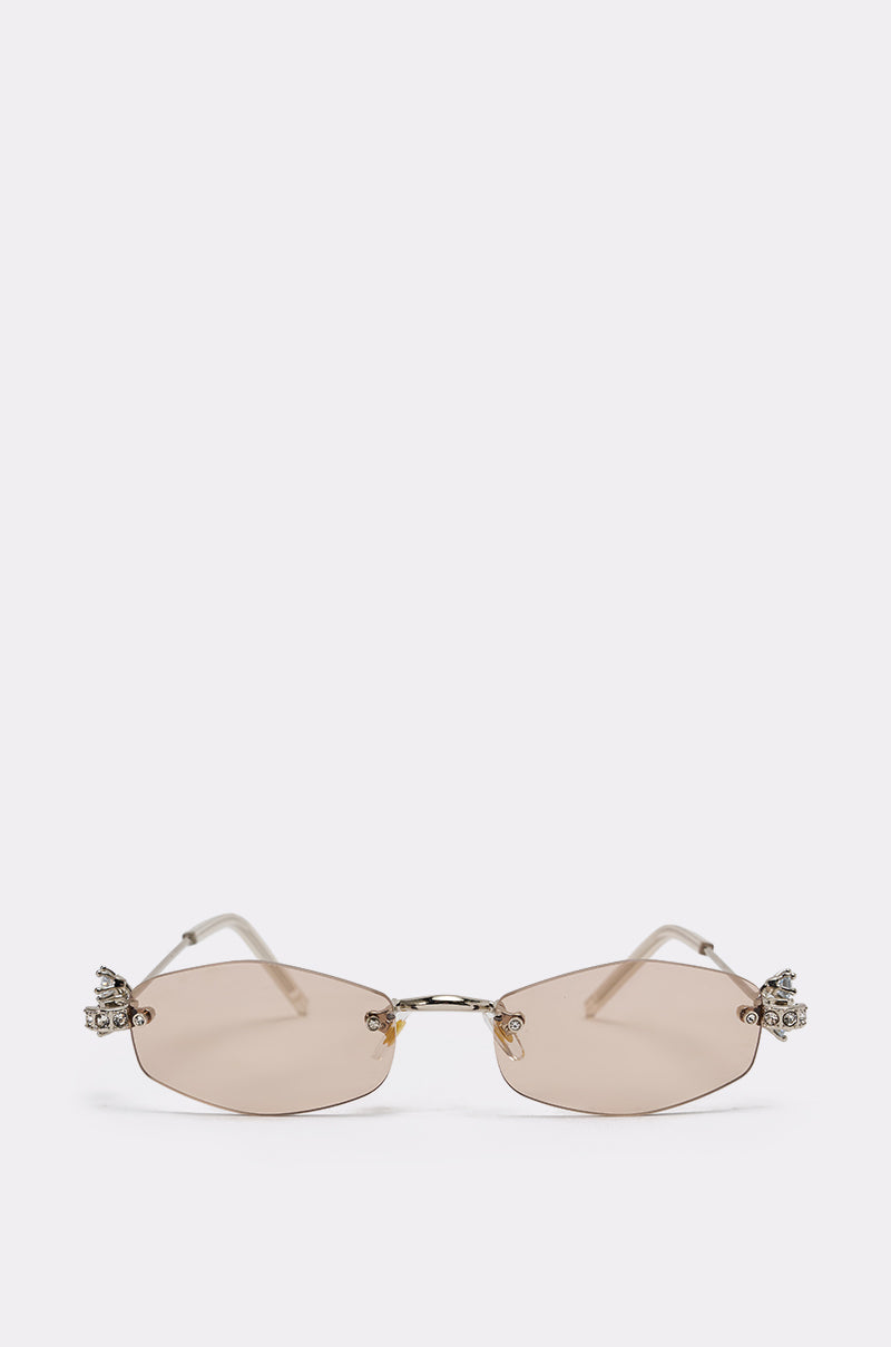 TRENDSTER GLASSES: Y2K oval sunglasses with light brown tinted lenses, small jeweled accents at the outer corners, and a subtle silver-tone metal frame, shown against a plain white background. 4
