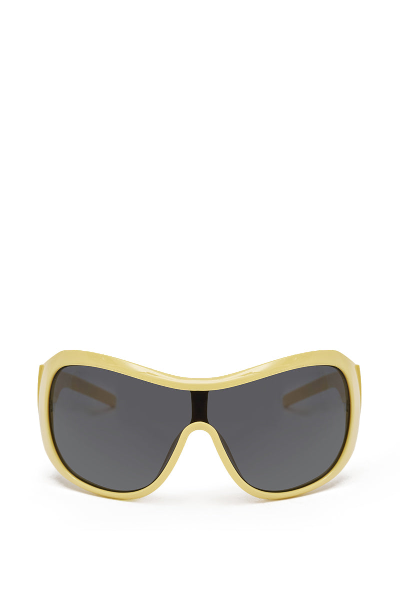 The BUTTA SUNGLASSES feature an oversized yellow shield design with large, curved wraparound black lenses, making a bold streetwear statement against a plain white background.