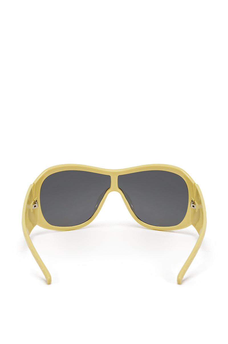 A pair of BUTTA SUNGLASSES featuring oversized yellow frames and dark lenses, displayed from the back with open temples facing forward against a white background. 2