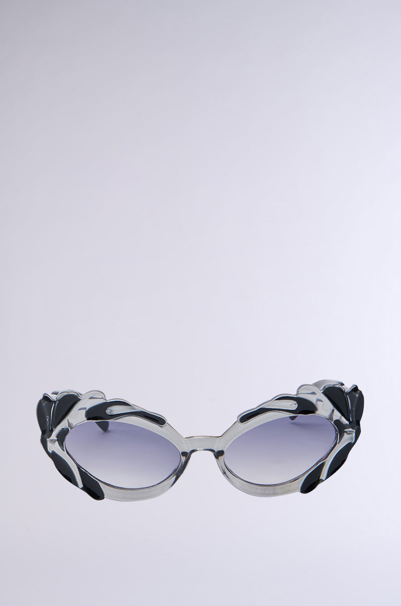 These "OUT OF THIS WORLD SUNGLASSES" feature thick, decorative frames with black and metallic accents. The stylish cat eye design has oval-shaped lenses with a subtle gradient tint against a plain background, showcasing fashion accessories at their finest.