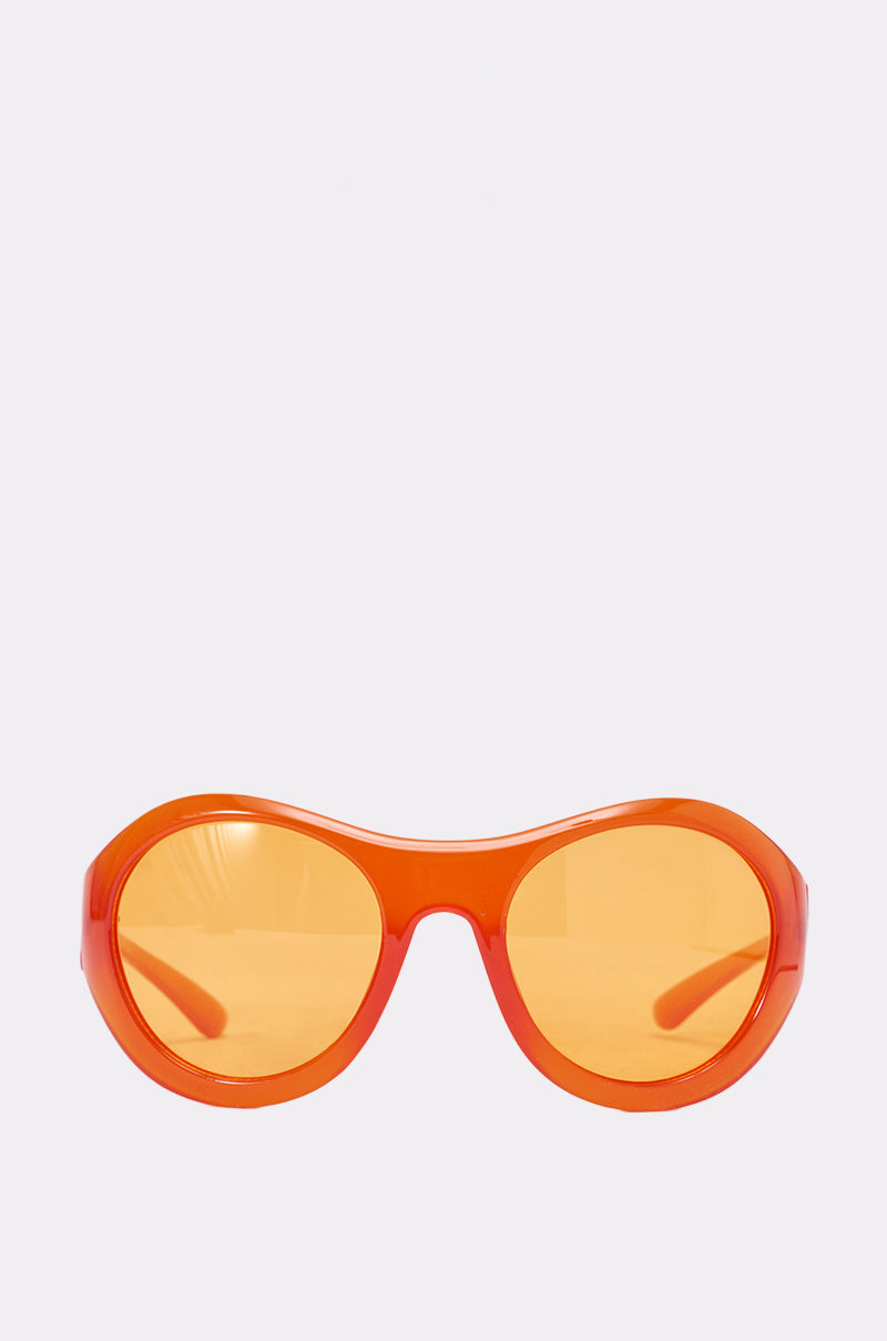 The IN YOUR WORLD SUNGLASSES feature bright orange oversized oval frames with matching orange-tinted lenses, displayed against a plain white background. 0