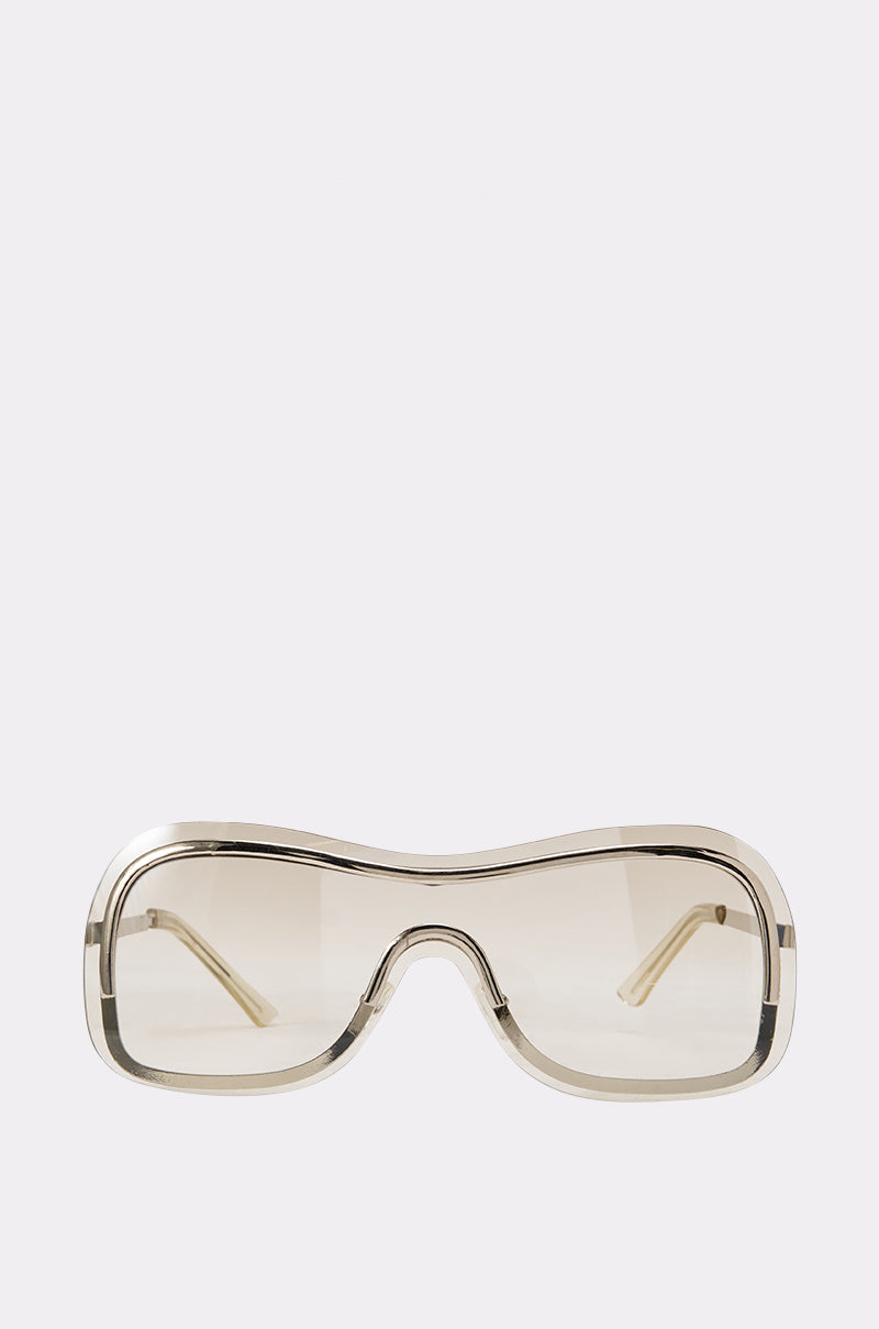 The SHEER DIVA FRAMES feature a beige, oversized rectangular wraparound design with lightly tinted lenses, capturing a retro-chic vibe that makes them the ideal accessory for effortless summer style. Displayed against a plain white background.