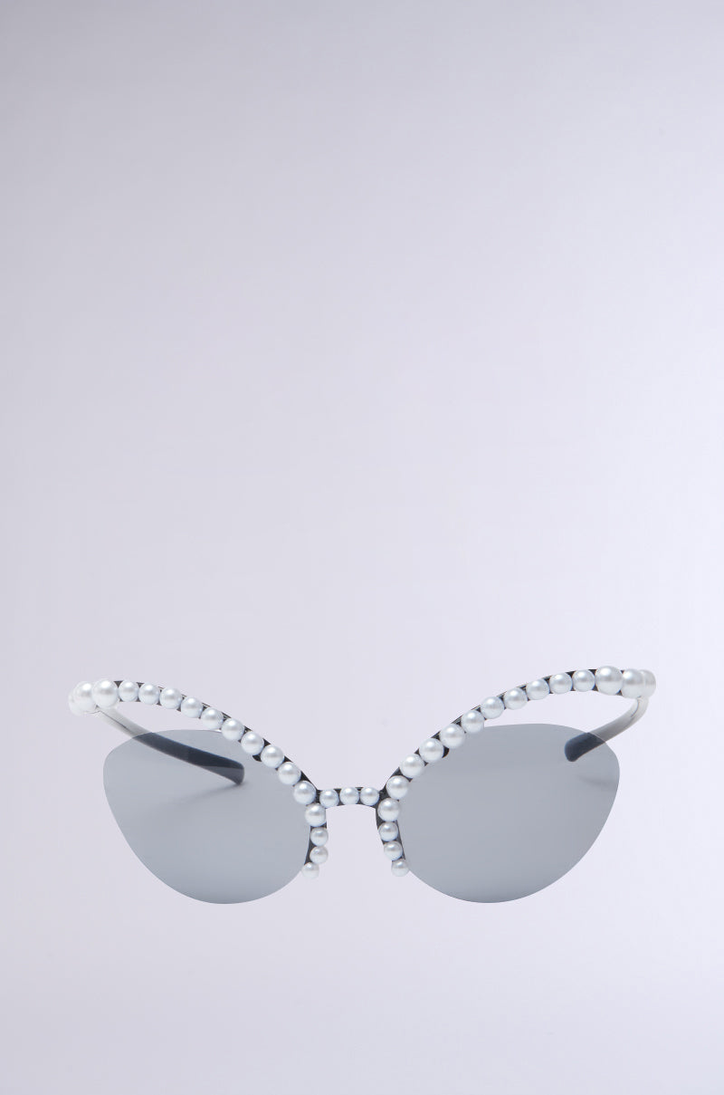 The DONT BUG SUNGLASSES feature cat-eye frames with reflective silver lenses, adorned with pearl embellishments on the frame and temples. The backdrop is a light gray gradient.
