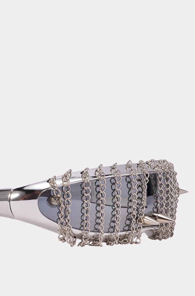 The CHAINED DOWN SUNGLASSES feature dark lenses, multiple silver chains draped across the front, and spikes on the frame for an edgy, avant-garde festival look. 3