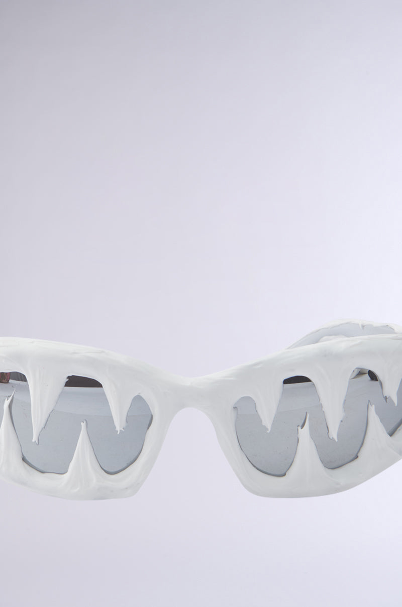 ICED OUT SUNGLASSES feature a white, drippy frame with melting ice or wax-like texture and icicle-inspired details, set against a plain light gray background.