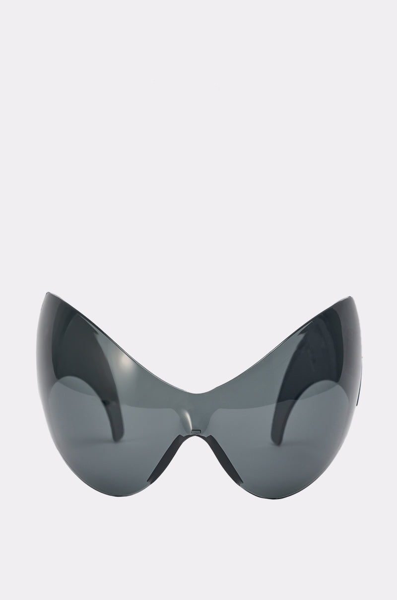 IM BETTER SUNGLASSES feature a futuristic, oversized shield silhouette with a wraparound design and dark reflective lenses, displayed against a plain white background. 1
