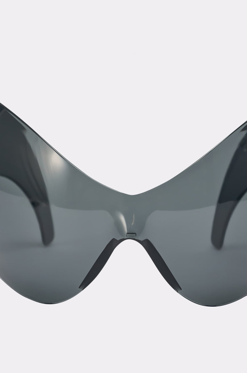 Close-up view of the front of IM BETTER SUNGLASSES, featuring dark, reflective wraparound lenses against a plain light background—perfect for elevating any streetwear look. 4