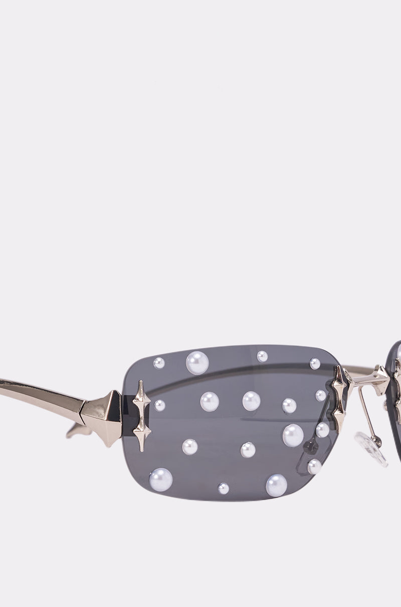Close-up of MIDNIGHT DRIP SUNGLASSES with pearl embellishments, rectangular dark lenses, and star-shaped gold accents—these frameless sunglasses are the perfect standout accessory for any festival look. 3