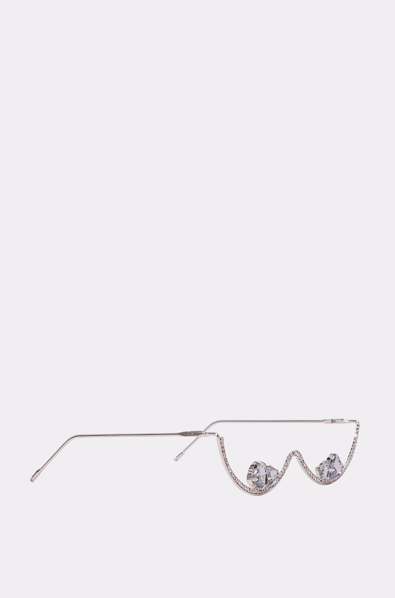 The DIAMOND DRIFT SUNGLASSES feature thin silver frames, rhinestone detailing, and uniquely wavy lenses adorned with small decorative elephant figures along the lower edge, set against a plain light-colored background. 3