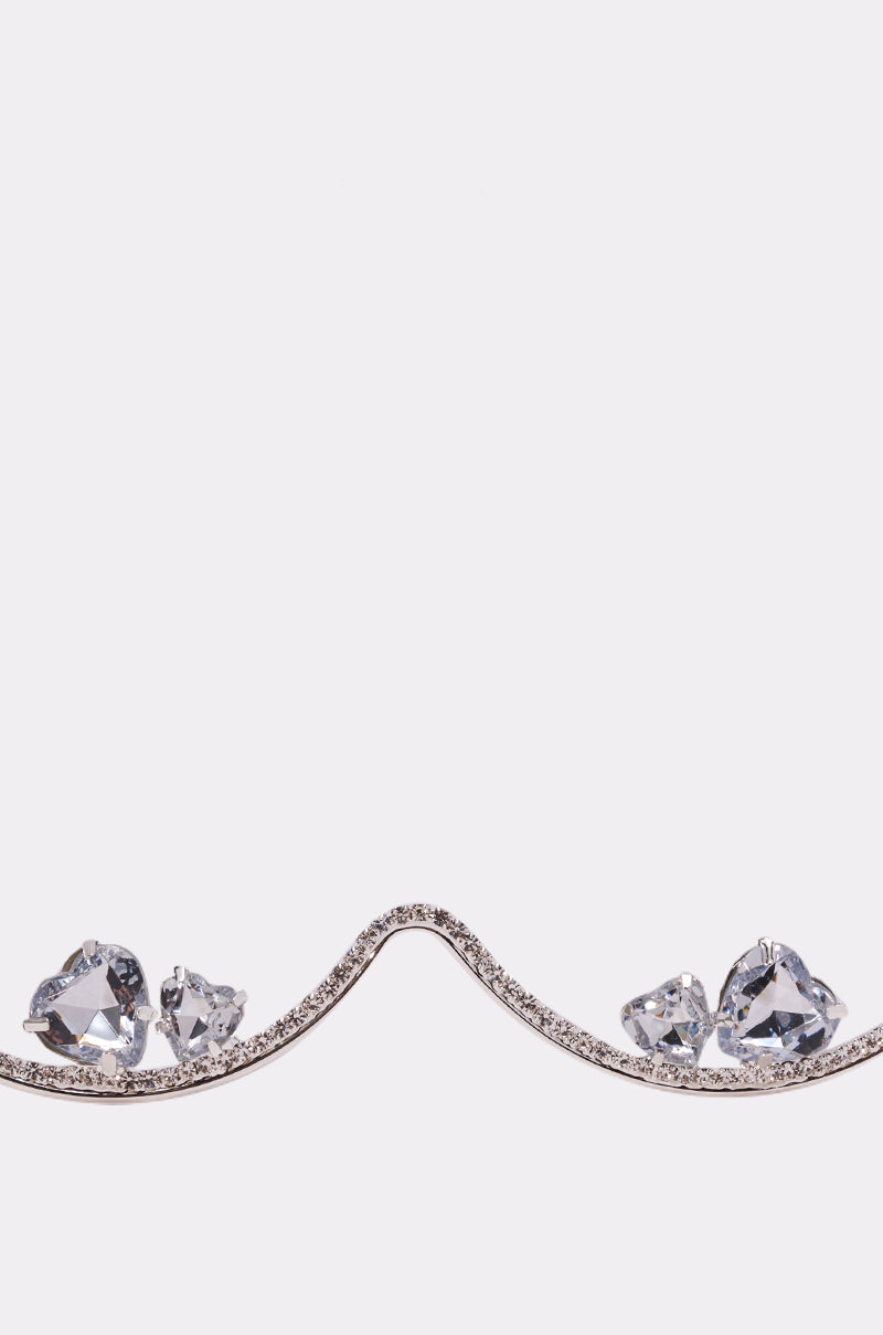 A curved silver line adorned with small gems forms a wave, resembling the DIAMOND DRIFT SUNGLASSES, with clusters of large clear faceted stones at each dip, set against a plain white background. 4