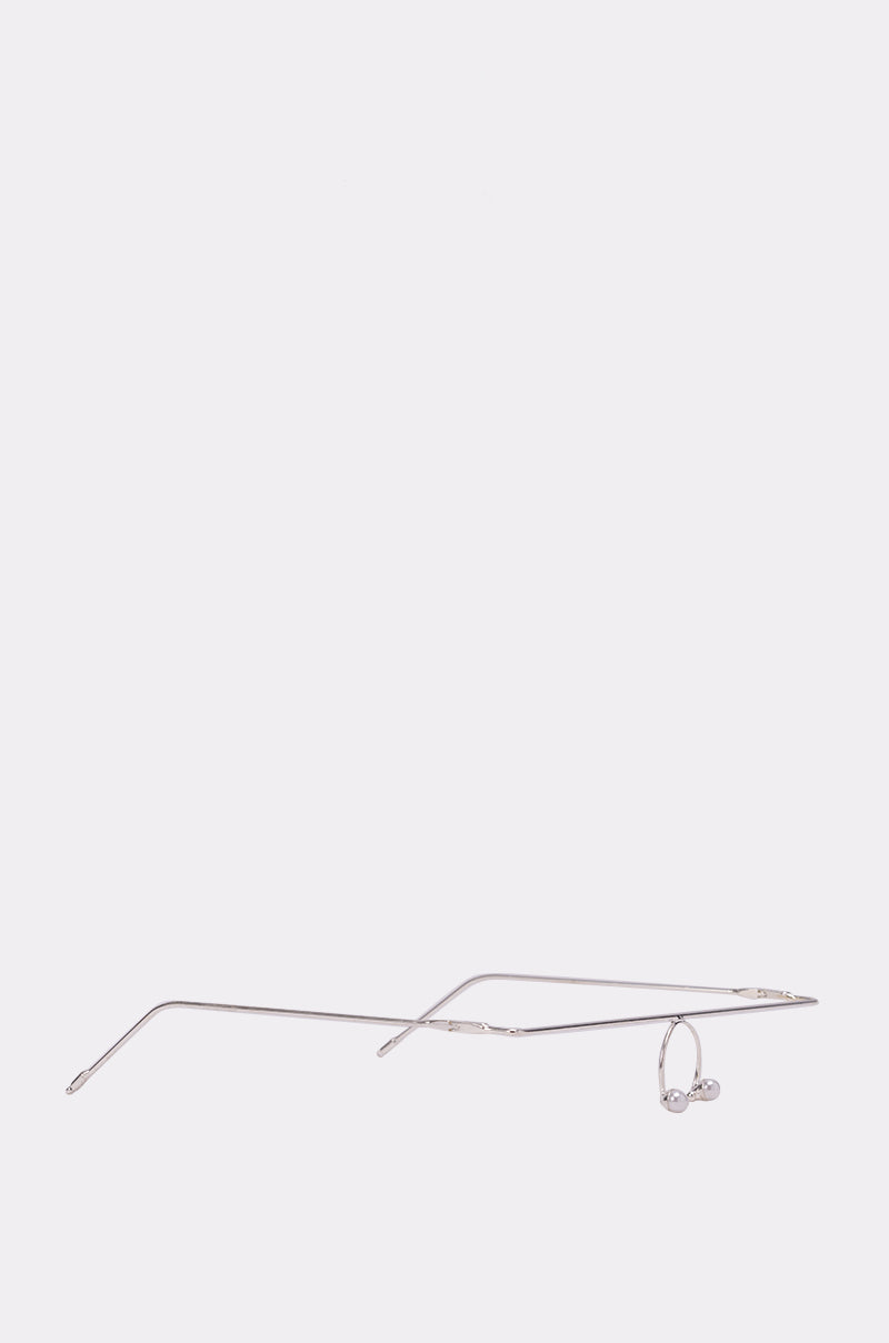 The NOT ME SUNGLASSES, featuring a minimalist and lightweight design, rest on a plain light gray background—making them an ideal editorial festival accessory for discreet use. 2