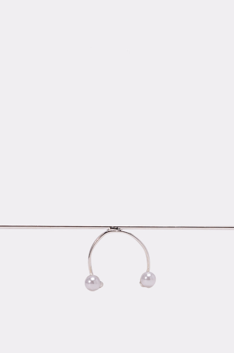 The NOT ME SUNGLASSES rest elegantly on a slim metal rod, their minimalist silver frames and pearl-like accents evoking the look of refined statement eyewear against a plain white background. 3