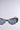 The VENOM LOVE SUNGLASSES, featuring sleek black cat-eye frames with silver side and top accents and metallic snake-inspired detailing on a light gray background, boast dark tinted lenses.