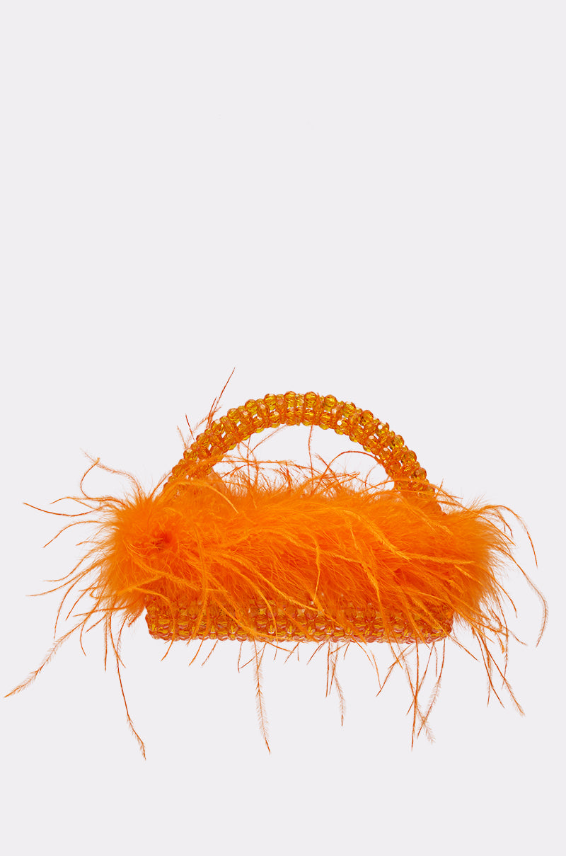 The NIGHT OUT BEADED FEATHER BAG is a rectangular orange handbag with a beaded handle and bold feather trim at the top, displayed on a simple light background. 0