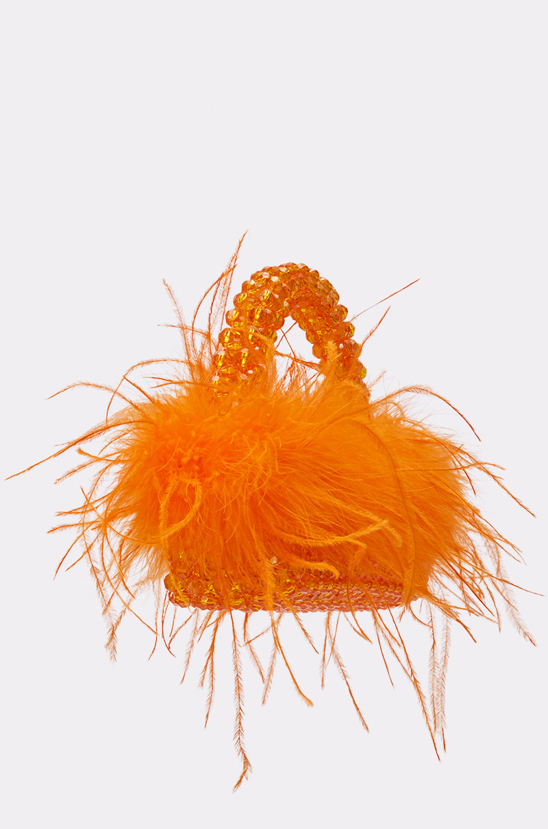 The NIGHT OUT BEADED FEATHER BAG is a small, bright orange handbag with fluffy feathers and a beaded handle, shown on a plain white background. 2