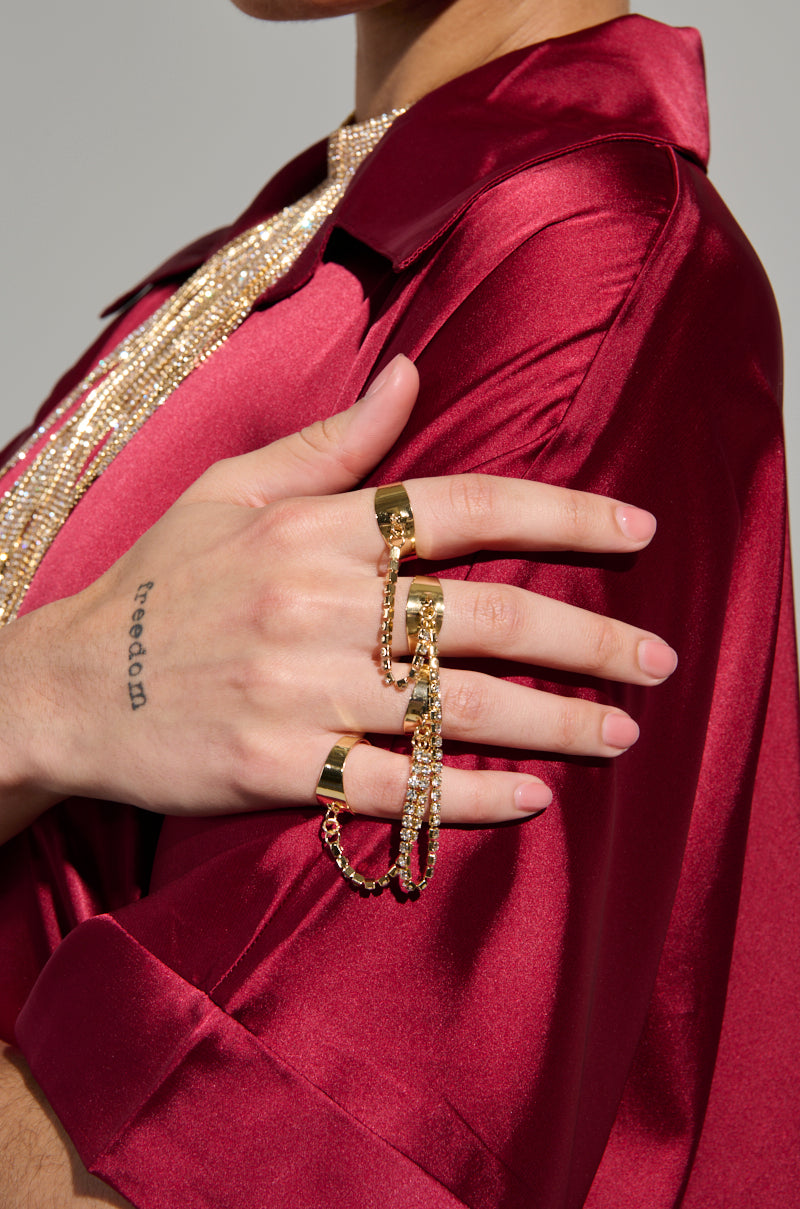A person wearing a shiny red shirt, with the STAY CONNECTED BLING RING SET sparkling across their hand. A tattoo with the word "freedom" graces their wrist, adding a touch of individuality to the rhinestone-embellished ensemble.