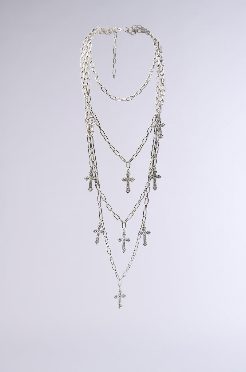 The LAYERS TO THIS CROSS NECKLACE is a multi-layered faux silver chain with rhinestone-encrusted cross pendants, shown against a light gray background. 0