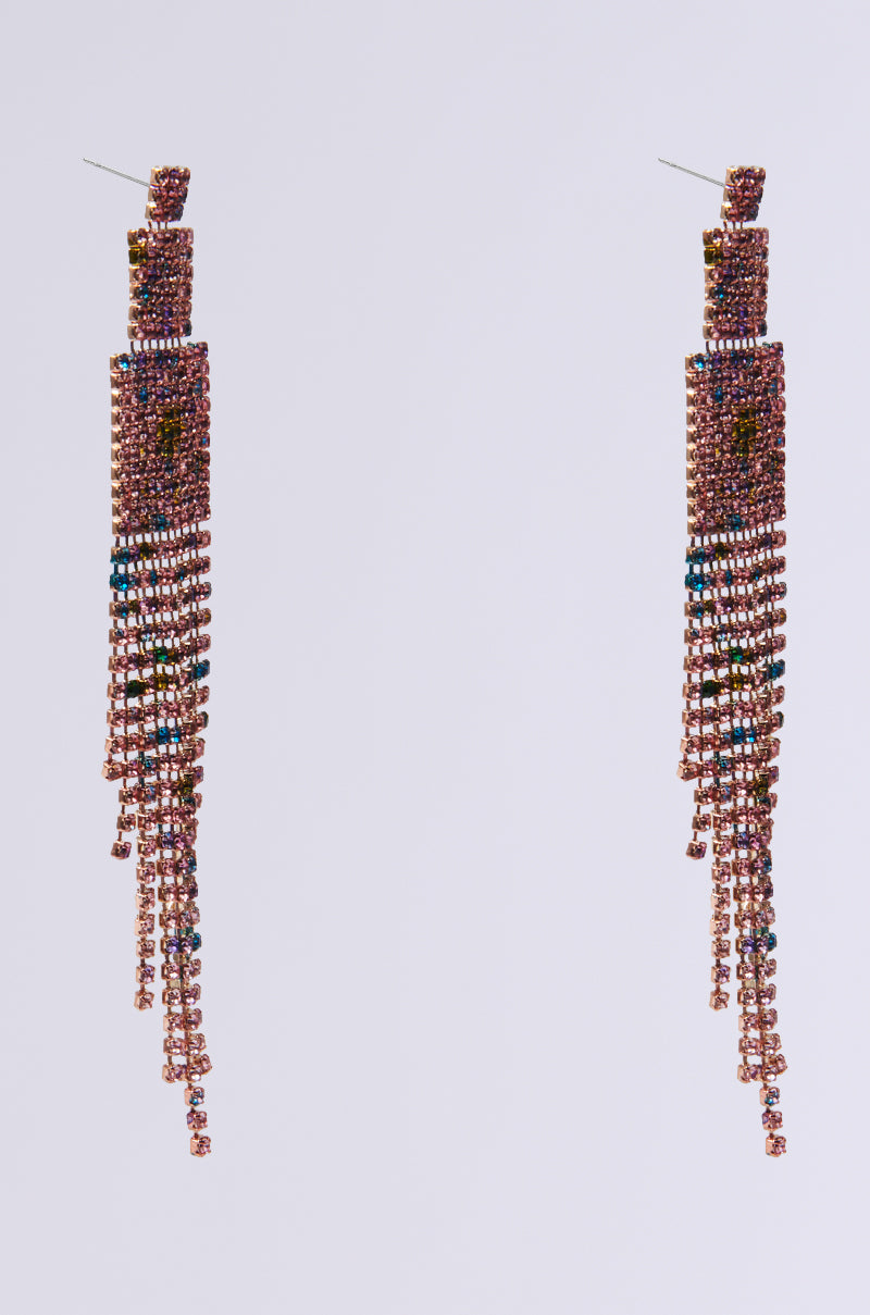 The RAINBOW DREAMING DANGLE EARRING showcases an elegant, long chandelier design adorned with a cascading fringe of rhinestone chain links. Strands of pink, blue, and gold embellishments shimmer against a plain gray background, creating a captivating multicolor effect.