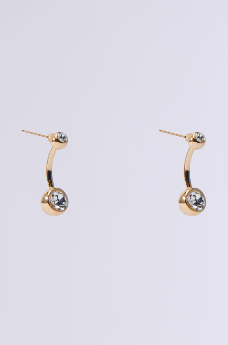 The MADE YOU LOOK EARRING features a modern design with gold curved stems and round, faceted rhinestones. These elegant earrings shine brilliantly against a neutral light gray background, adding sophistication to any ensemble.