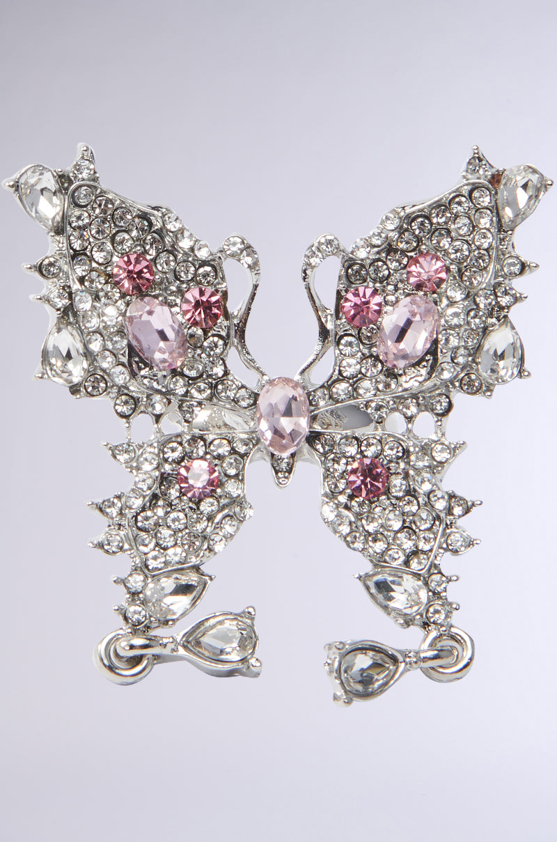 The TOO PRETTY FOR YOU RING showcases a butterfly design with clear and pink gemstones set in silver, featuring intricate wing detailing with round and teardrop-shaped stones, highlighted by a large central pink stone.