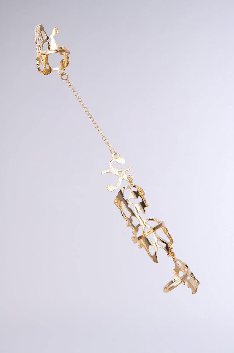 The EVA TWO FINGER RING SET, with its intricate floral cut-out patterns and delicate chain links, exudes elegance against a gray background, embodying the sophisticated artistry of the AKIRA Label.
