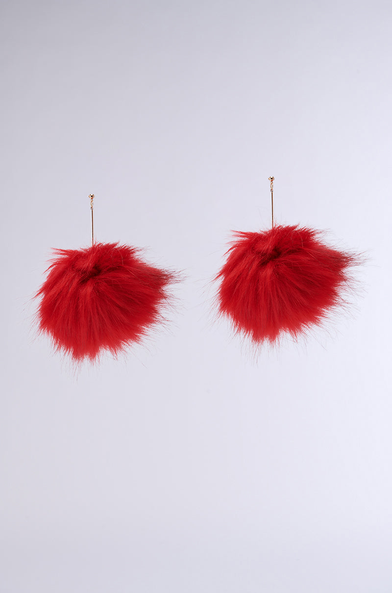 A pair of MAMI FUR EARRING in red, featuring fluffy pom-poms with thin faux metallic gold hooks, set against a plain, light grey background. 2