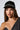 A woman with long, light brown hair wears the SPIKED SNAPBACK, featuring silver and black rhinestone embellishments. She is dressed in a black off-shoulder top with metallic details and poses against a plain background. Her expression is neutral, her direct gaze captivating.