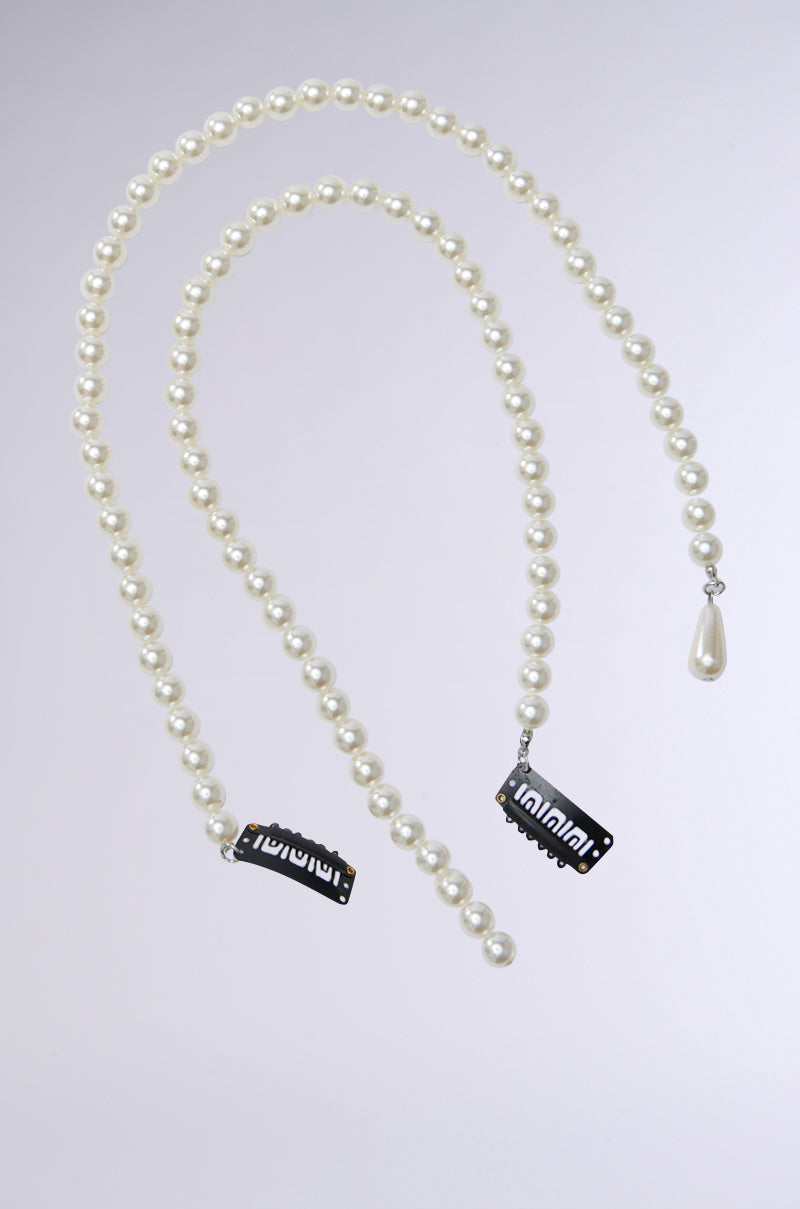 A necklace with a large teardrop pearl on one end and black rectangular clips featuring white text on the other, inspired by PEARL GODDESS HAIR CLIP SET, displayed against a light gray background. 3
