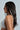 A person with long dark hair adorned with the Pearl Goddess Hair Clip Set wears a white, pearl-embellished top. Facing left against a plain background, they highlight the intricate details of their outfit and accessories.