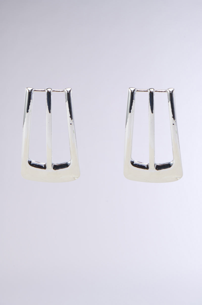 A pair of BUCKLE UP EARRINGS in geometric, metallic faux silver, featuring open spaces that give them a sleek and modern look, set against a plain, light grey background.