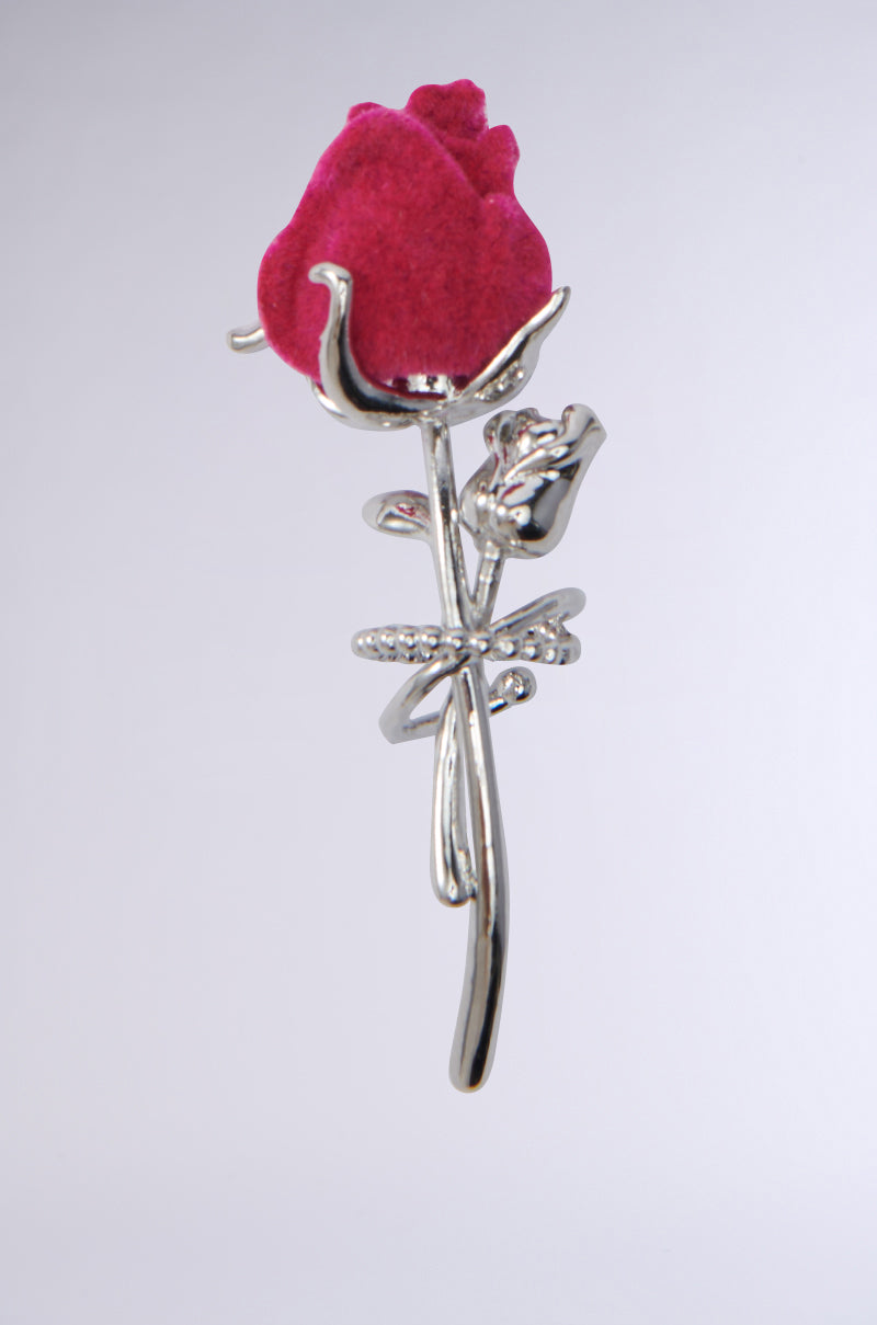 The ROSEBUD EAR CUFF is a silver ear accessory with a fuchsia flower centerpiece, featuring detailed metallic silver leaves and stem designs. The background is a plain, soft gray. 1