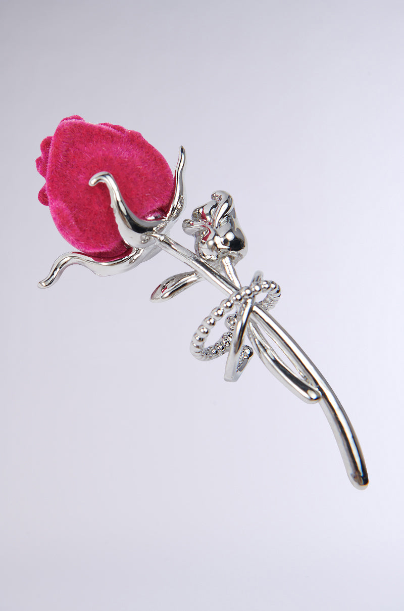 The ROSEBUD EAR CUFF features a metallic silver design with a vibrant pink felt rose and intricately textured stem and leaves, all set against a neutral gray background. 2