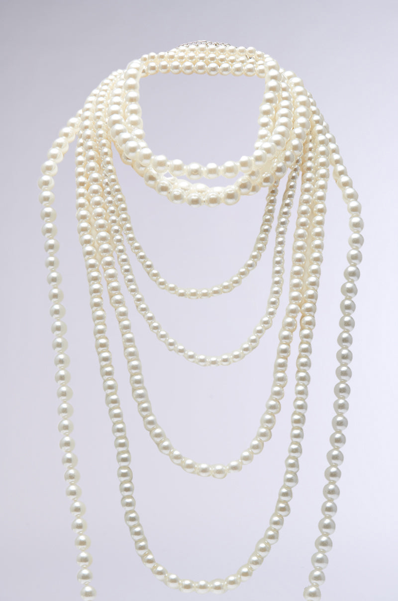 The PENELOPE STATEMENT PEARL NECKLACE showcases a stunning choker-style design with elegant white pearls arranged in multiple overlapping layers against a plain background.
