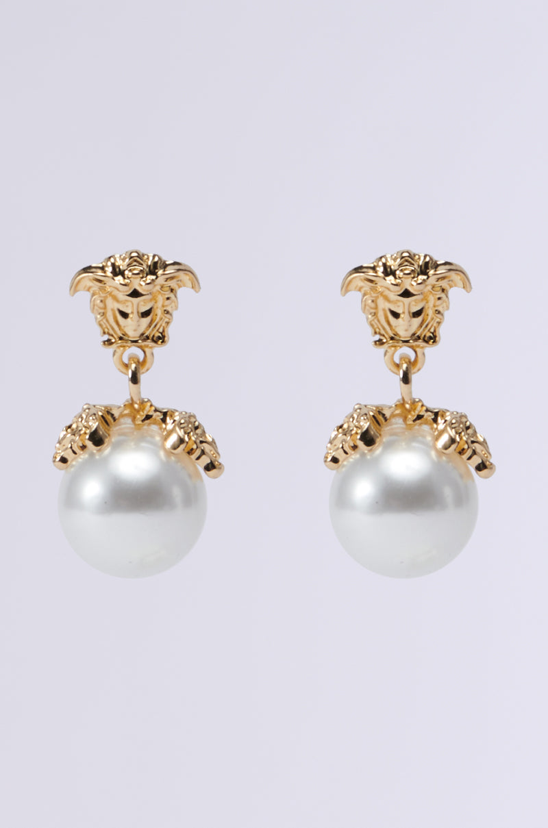 The MANSION VIBES EARRING features elegant gold-tone drop earrings adorned with intricate lion head designs at the top and large faux pearl-like orbs hanging below, accented by small crystal details—perfect for those who love a touch of sophistication.