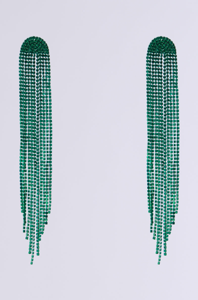 The EMERALD ROAD EARRING features a pair of long, elegant green tassel designs, composed of multiple strands of small beads gracefully cascading downwards and complemented by subtle rhinestone-encrusted accents. This statement jewelry piece stands out beautifully against a plain white background.