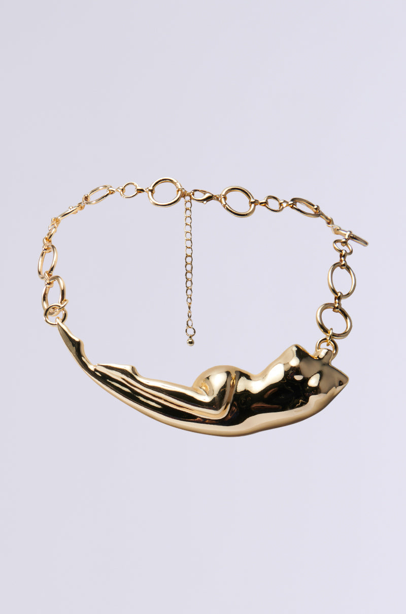 The I AM WOMAN NECKLACE is a standout piece with a large, abstract nude female form pendant. It includes a faux gold chain of interconnected oval links and an adjustable clasp with an extra chain for length customization, all set against a plain gray background.