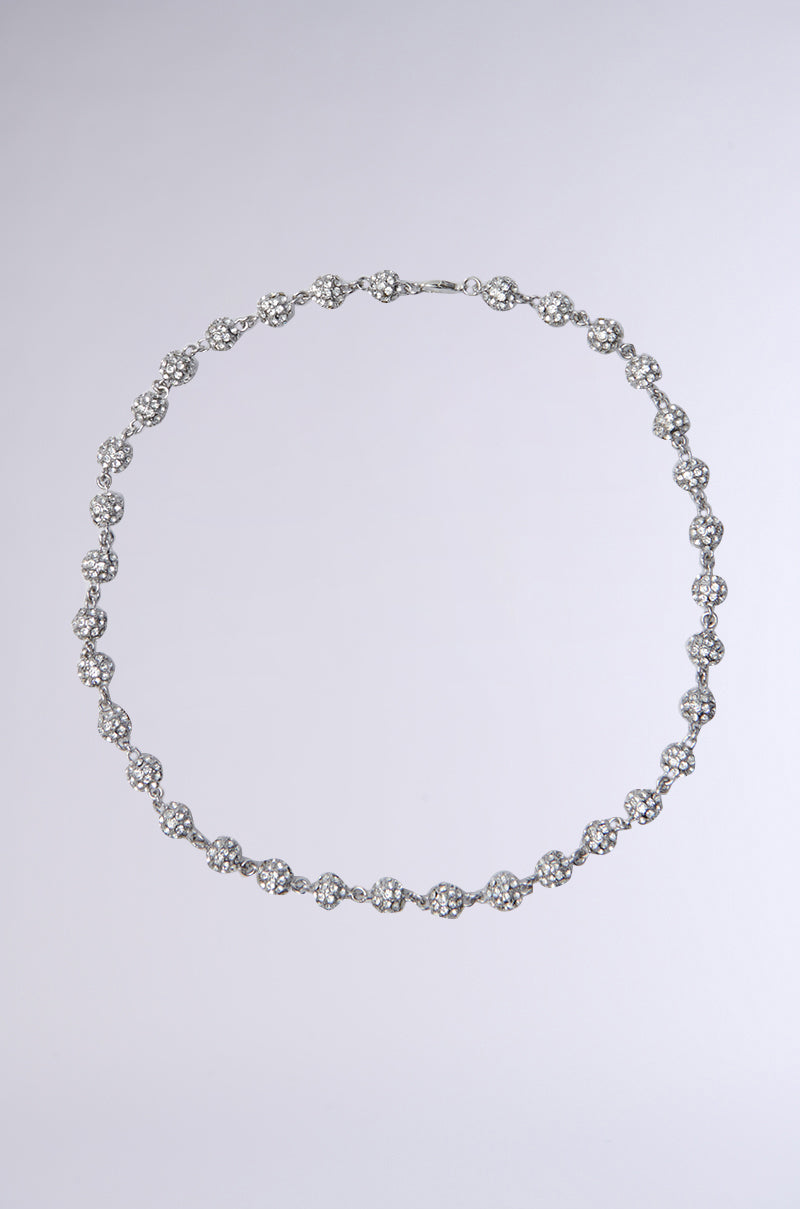 The QUEZ PAVE STONE CHAIN is a delicate silver necklace, featuring interlinked flower-shaped diamond clusters symmetrically arranged in a circular design against a plain gray background.