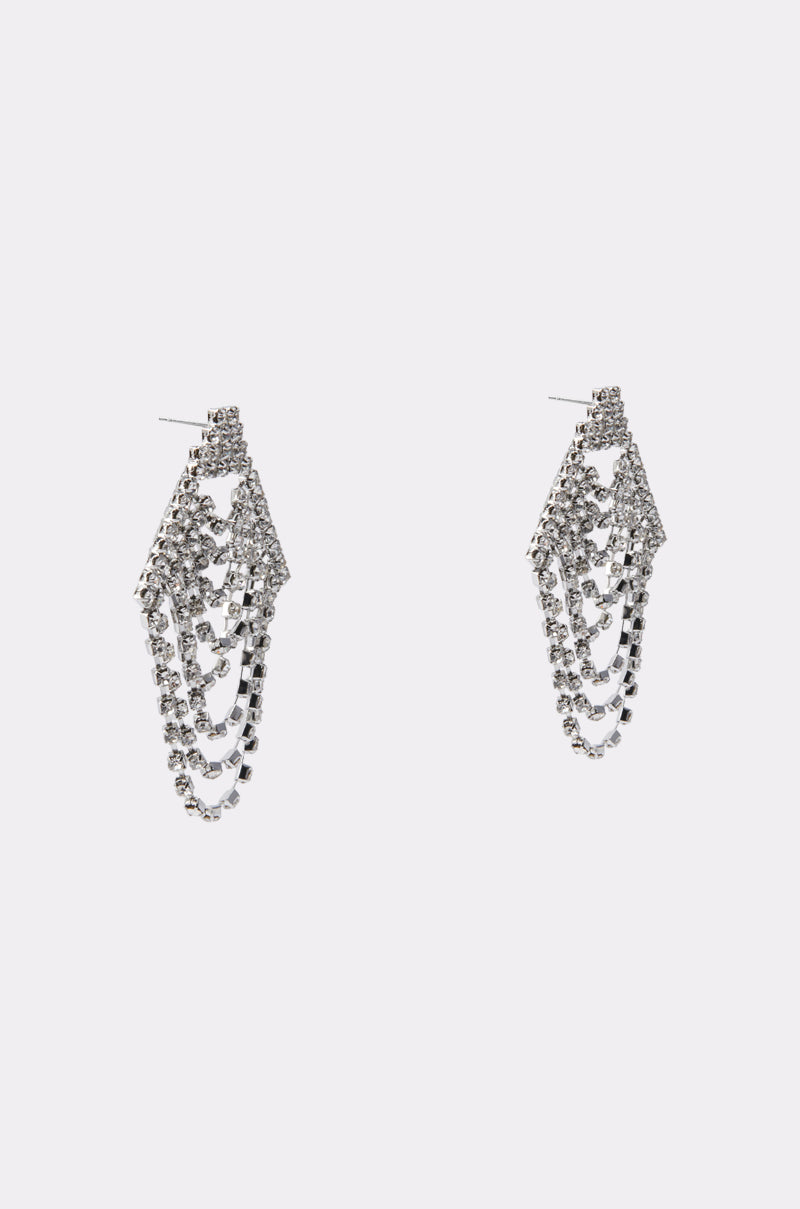 The TO THE GALA EARRING IN SILVER by AKIRA features chandelier-style design with layered draped chains and multiple rows of sparkling rhinestones, creating an elegant look. Shown against a plain white background.