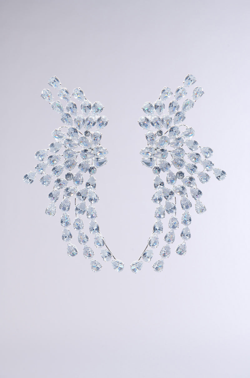 TAYTAY STATEMENT EARRINGS, featuring elegant and sparkling clusters of crystals that cascade beautifully, are showcased against a simple, light backdrop. 1