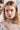 Two models wearing sparkling crystal earrings and necklaces. The main focus is on one model with long blonde hair and large TAYTAY STATEMENT EARRINGS that feature a swooping abstract design, framed between silver chains. The background is softly out of focus with a decorative pattern.