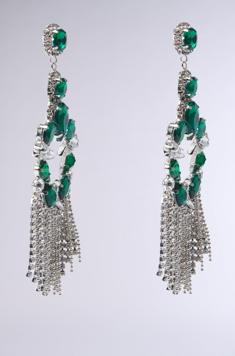 These Emerald Dreams Statement Earrings feature green gemstones, silver accents, and a cascading rhinestone fringe detail set against a light gray background, embodying pure elegance. 2