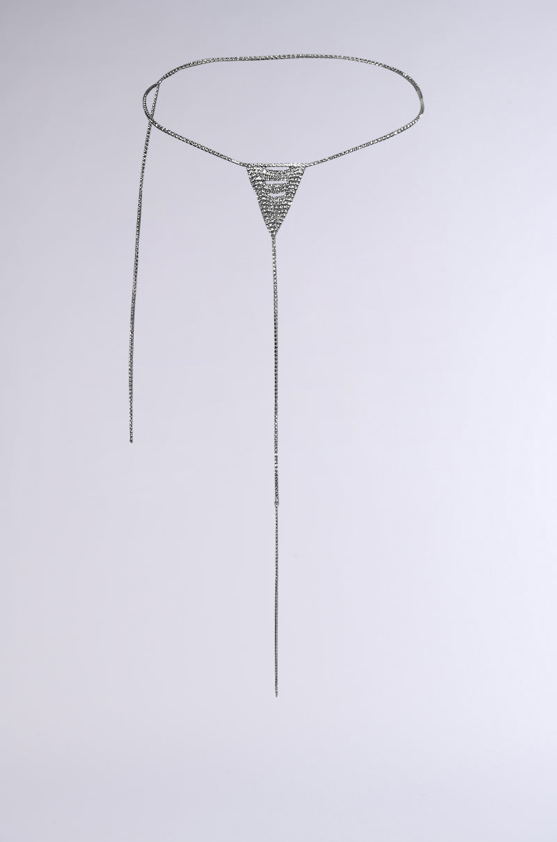 The OOPS MY THONG CHAIN BELT is a minimalist silver accessory featuring rhinestone links and a center triangular pendant. It hangs against a plain white background, with two long, thin chains extending downward to create an elegant statement piece.