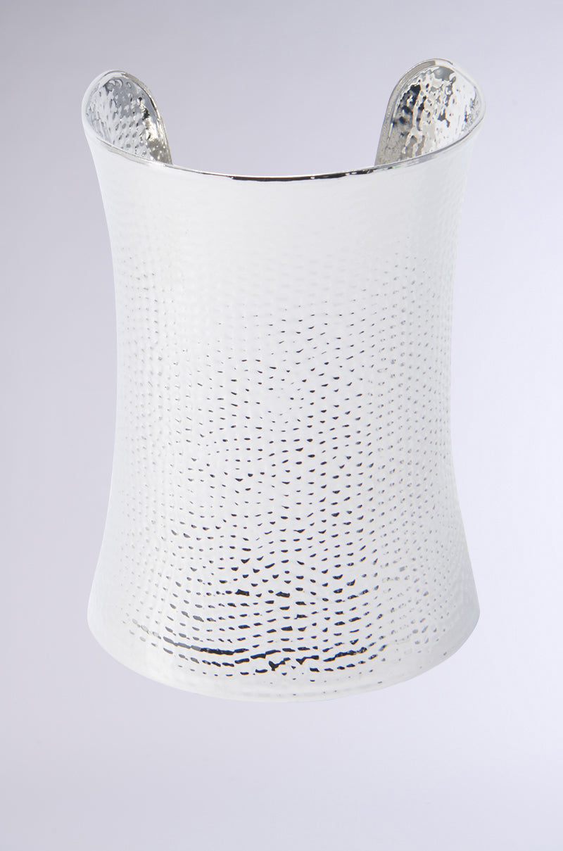The ART DECO BRACELET CUFF, featuring a shiny textured faux silver design, is displayed on a light gray background. This wide bracelet has a slightly tapered cuff shape and showcases a hammered metal finish that beautifully enhances its reflective surface.